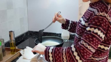Kadın modern mutfakta kahvaltı için yumurta pişiriyor.
