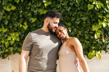 Romantik dansçılar güneşli bir günde sarmaşık duvarının yanında kucaklaşırlar.