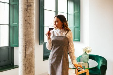 Profesyonel şarap garsonu yeşil pencereli şık restoranda kırmızı şarap kokluyor ve tadıyor.