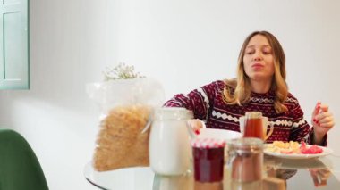 Mutlu kadın kahvaltı kasesine şeker ekliyor.