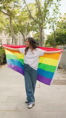 Gökkuşağı bayrağına sarılı mutlu genç kadın lgbtqia 'yı kutluyor artı gurur ayı