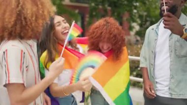 Mutlu çoklu etnik arkadaşlar lgbt gururunu gökkuşağı bayrakları ve hayranlarıyla kutluyor.