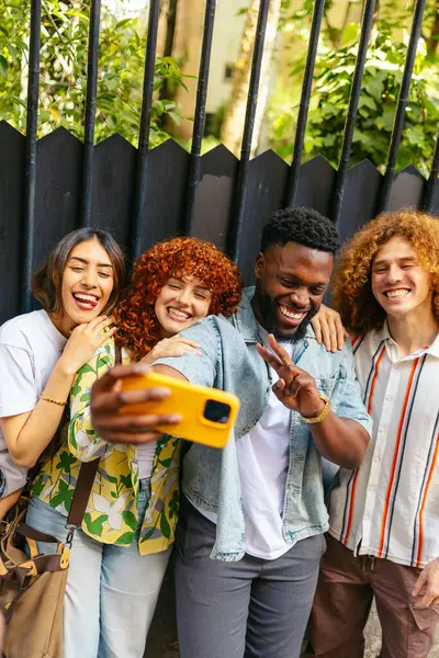 Dört neşeli çoklu etnik arkadaş dışarıda selfie çekiyorlar, eğleniyorlar ve eğleniyorlar.