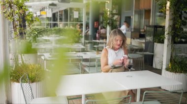 Açık hava restoranında ruj süren zarif bir son sınıf öğrencisi.