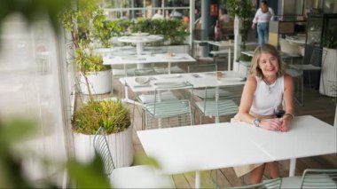 Şık bir son sınıf öğrencisi, açık hava restoranında elinde şarapla bekliyor.