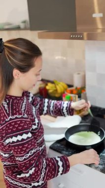 Modern mutfakta kahvaltı için krep pişiren bir kadın.