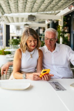 Üst düzey bir çift birlikte vakit geçiriyorlar, restoranda akıllı telefon kullanıyorlar.
