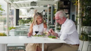 Üst düzey çift açık hava restoranında şarap ve salatanın tadını çıkarıyor.