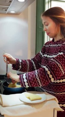 Kadın mutfakta kahvaltıda krep pişiriyor.