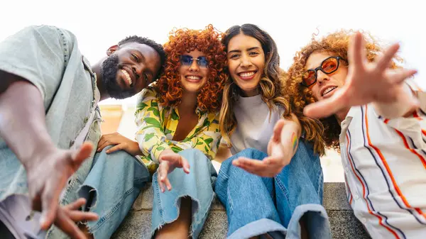 Kameraya uzanan dört neşeli genç arkadaş, birlikte dışarıda vakit geçirmenin tadını çıkarıyorlar.