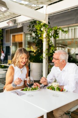 Üst düzey çift açık hava restoranında şarap ve salatanın tadını çıkarıyor.