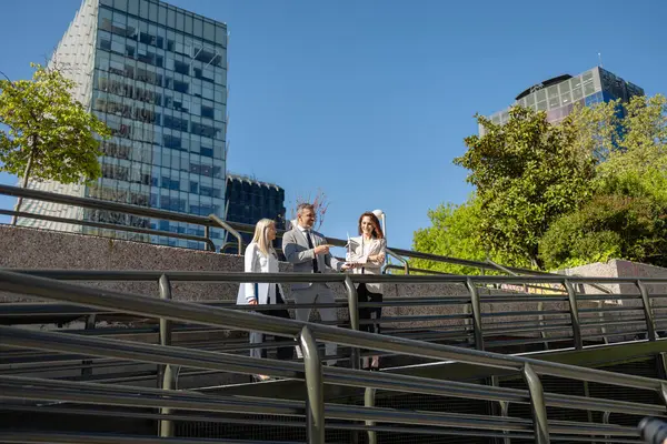 Kentsel bir ortamda yenilenebilir enerji stratejilerini tartışan üç profesyonel