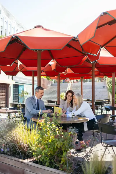 Profesyoneller kırmızı şemsiyeler altında dışarıda iş birliği yapıyorlar.