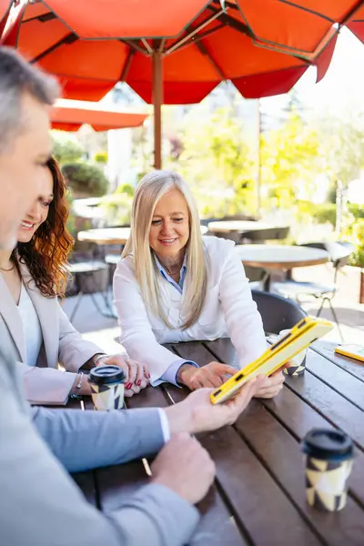 Tablet kullanan işadamları, açık havada sözleşmeyi tartışıyorlar.