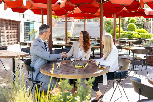 Açık kafede yapılan başarılı anlaşmanın ardından iş adamları el sıkışıyor