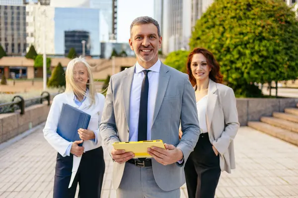 Ekonomik bölgede gülümseyen ve belgeleri elinde tutan iş adamları