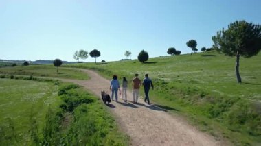 Mutlu aile parkta piknik sepetleri ve köpeklerle yürüyor.