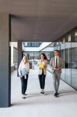 Modern ofis binasında iş adamları yürüyor ve konuşuyor