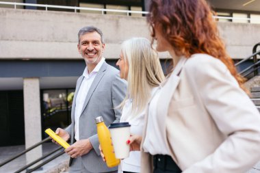 İş adamları ofis binası dışında yürüyor ve konuşuyorlar