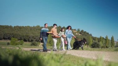 Güneşli bir günde köpekleriyle birlikte yürüyorlar piknik sepetleri taşıyorlar ve dışarıda eğleniyorlar.