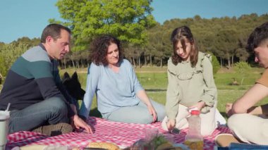 Aileleri piknikten ve parklarda kağıt oynamaktan zevk alıyor, yanlarında köpekleri var.