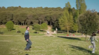 Baba ve kızı güneşli bir günde parkta birlikte oynuyorlar.