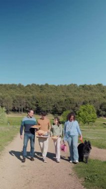 Güneşli bir günde köpekleriyle birlikte yürüyorlar piknik sepetleri taşıyorlar ve dışarıda eğleniyorlar.