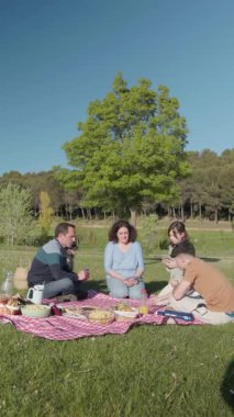 Parkta köpeğiyle güneşli pikniğin tadını çıkaran bir aile.