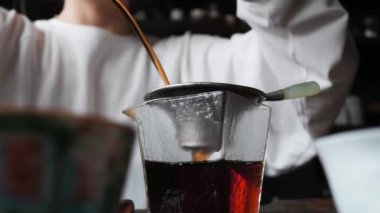 Çayhanedeki açık renk elbiseli genç kadın çaydanlıktan cam bir sürahiye çay dolduruyor. Düşük açılı Çin çay seremonisi konsepti.