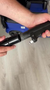 Siyah bir hortumu basınç makinesine bağlayan yakın plan bir el, ekipman montajını gösteriyor..