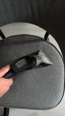 Gri döşemeli bir sandalyede ıslak süpürge hortumunu çalıştıran bir elin yakından, yüksek açılı görüntüsü tam bir temizlik rutinini gösteriyor..