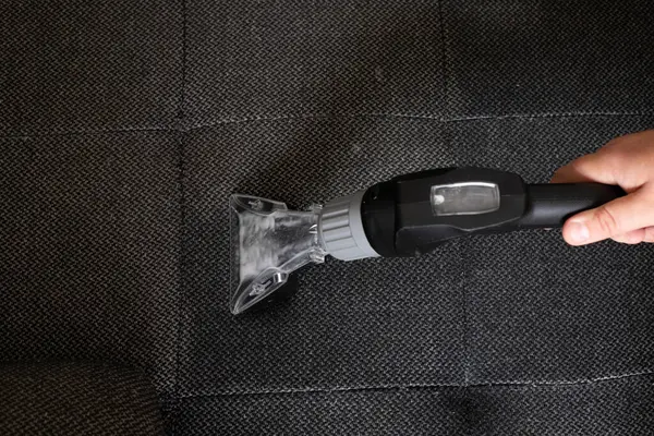 Gri bir kanepede ıslak bir elektrikli süpürge hortumunun yakın çekim görüntüsü etkili bir derin temizliğe hazır.