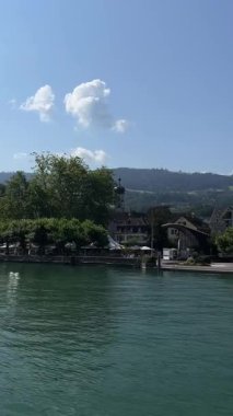 Constance Gölü 'nün (Bodensee) dalgalı, yeşil-mavi suları boyunca uzanan geniş panoramik bir manzara uzak kıyı şeridi Lindau' nun pitoresk limanına doğru uzanır.. 