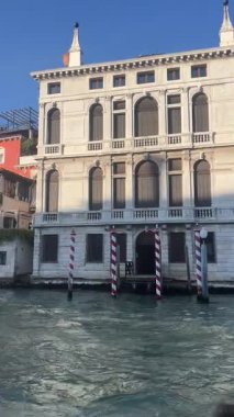 Klasik mimarisi ve koyu renk kepenkleri olan görkemli bir Venedik sarayı Büyük Kanal boyunca zarif bir şekilde duruyor. Karmaşık detaylar ve suya ince yansımalar sergiliyor..