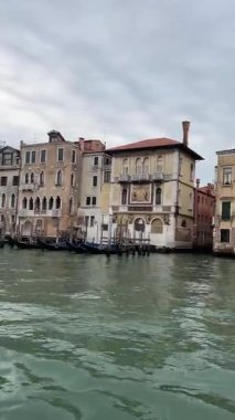 Venedik 'teki Büyük Kanal' da nefes kesici bir gün batımı, tarihi binalar ve suya yansıyan turuncu bir gökyüzü ve değişen ışıkta yüzen tekneler..