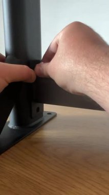 Duvara monte edilmiş bir çekiş çubuğunun siyah metal ekleminde sürgüyü ayarlayan bir insan eli yakın çekim, montaj sırasında hassas montajı gösterir.