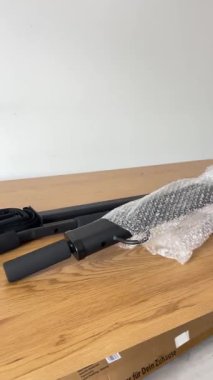 Bir barfiks çubuğunun birkaç siyah metal bileşeni, ambalajdan yeni çıkarılmış, boks işlemi sırasında hafif ahşap bir yüzeye serilmiş..