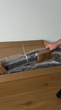 Bir insanın elleri, kutunun açılması sırasında çekiş çubuğu bileşenlerinin plastik ambalajını açmak için küçük bir alet bıçağı kullanır..