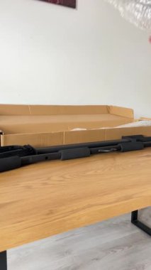 Yeni siyah çekiş çubuğu bileşeni, baloncuklu ambalaja sarılmış, karton kutusundan kısmen çıkarılmış, açık ahşap bir yüzey üzerinde..