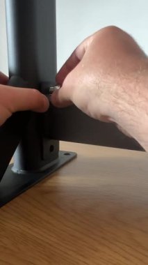 Siyah duvara monte edilmiş bir barfiks çubuğunun, metal bileşenleri birleştirmek için araçlar kullanan elleri de içeren adım adım görüntülenir.