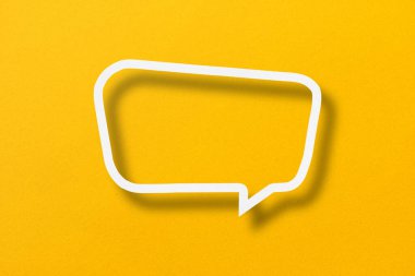 White paper cut out speech bubble shape set on yellow paper background.
