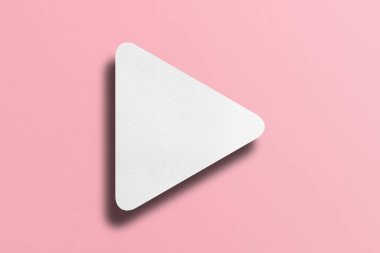 White paper cut into triangle shape, play button set on pink paper background.
