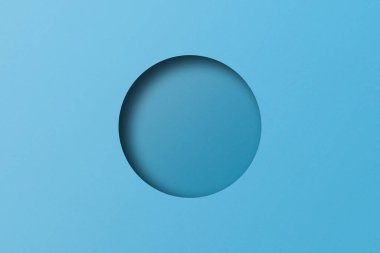 Light blue paper cut into circular holes stacked together with light and shadow.