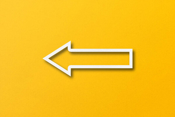 стрелка из белой бумаги на фоне желтой бумаги