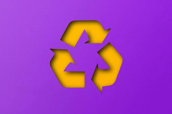 黄纸在紫色纸的背景上被切割成可循环利用的形状 — 图库照片