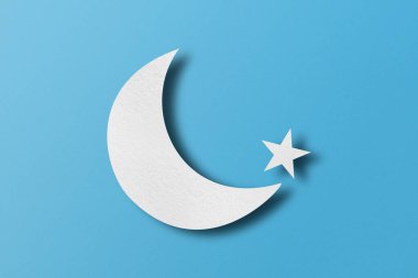 White paper cut into crescent shapes and stars set against a light blue paper background.