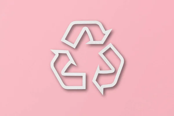 在粉色纸的背景上把白纸切割成可回收的形状 — 图库照片