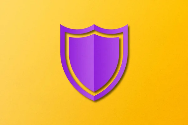 紫色の紙シールド黄色の紙の背景に設定されたカットシールド形状をパンチング — ストック写真
