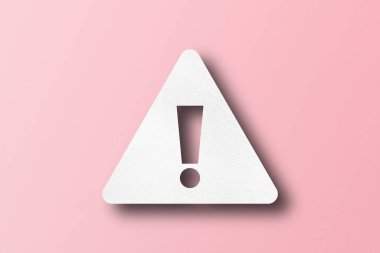 Beyaz kağıt, ünlem işareti şeklinde yumruklanmış. uyarı işareti pembe kağıt arkaplanda ayarlandı
