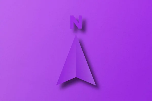 Purple paper cut in north arrow shape set on purple paper background.